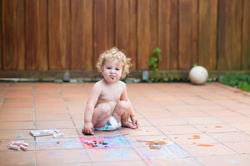 Funny little baby girl wearing a diaper paiting with chalk