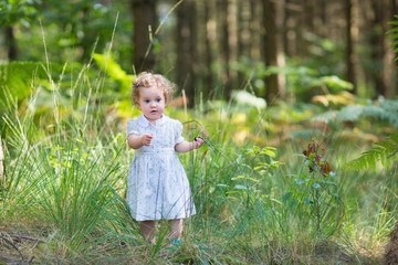 Baby girl wearing a white dress walking in a sunny autumn park