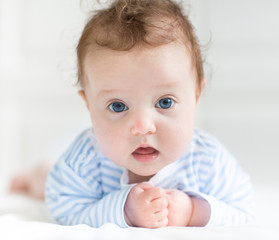 Funny cute little baby with big blue eyes playing on her tummy