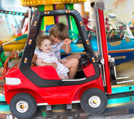 Brother and little baby sister enjoying a ride in an amusement
