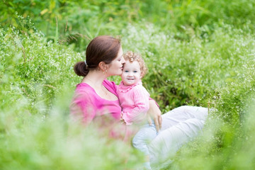 Pregnant mother and her baby daughter relaxing in the garden