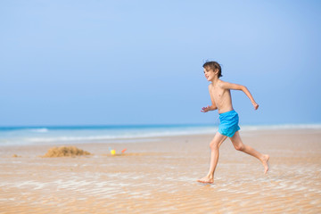 Fototapeta na wymiar Happy young boy running on a beautiful tropical beach