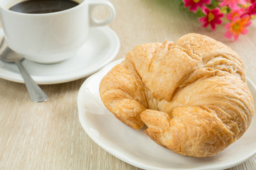 Fresh croissant with cup of black coffee