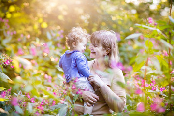 Beautiful woman with a happy baby girl in a garden at sunset