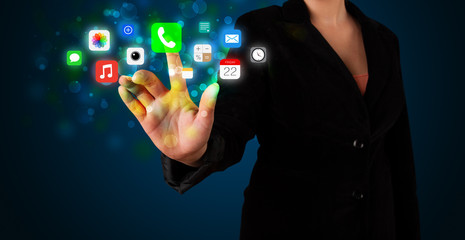 Young businesswoman pressing colorful mobile app icons with boke