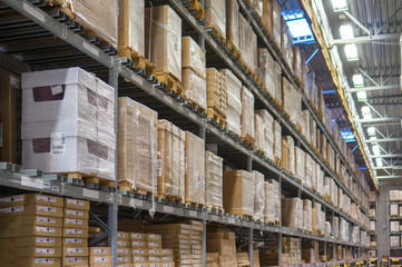 Rows of shelves with huge cardboard boxes in modern warehouse
