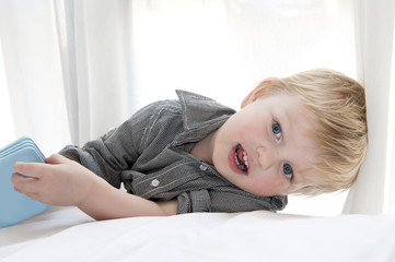 Fototapeta premium Cute little child lying on bed with book