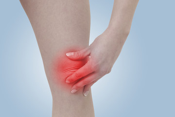 Acute pain in a woman  knee. Female holding hand to spot of knee