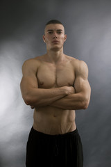 Young sexy man with athletic body on black background.