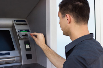 Young man put his credit card at the ATM