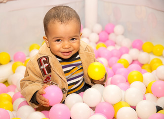 Fototapeta na wymiar Happy black boy in colored ball on birthday on playground.