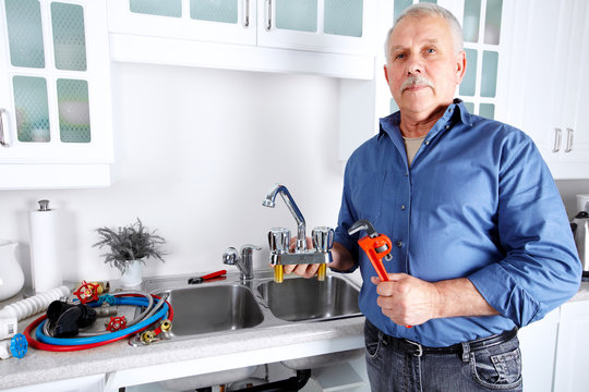 Plumber in kitchen with a wrench.