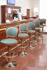Beautiful green classic chairs stand next to bar counter