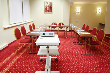 Projector, red chairs and tables in small room with red carpet