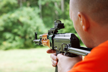Man aiming at a target and shooting an automatic rifle for strik