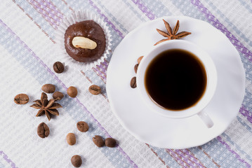 Cup of coffee decorated beans with little cake. Top view.
