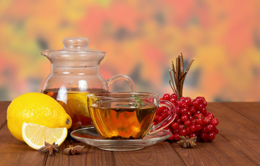 Tea with red viburnum and lemon on table