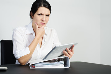 Verwirrte Frau brütet über einem Problem mit einem Tablet 