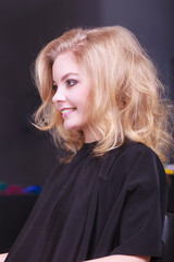 Fototapeta premium Beautiful girl blond wavy hair in hairdressing beauty salon