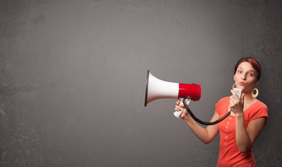 Girl shouting into megaphone on copy space background