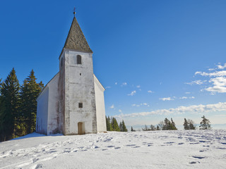 Fototapeta na wymiar Small church on snowy hill. Slovenia, Areh, Maribor
