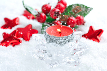 A christmas candle is with decorations on snow