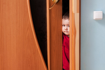 Child peeking from behind the door