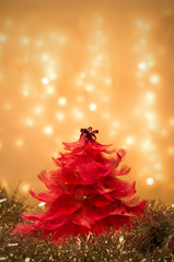 Dekoracja świąteczna - czerwona choinka z piórek na tle z lampek