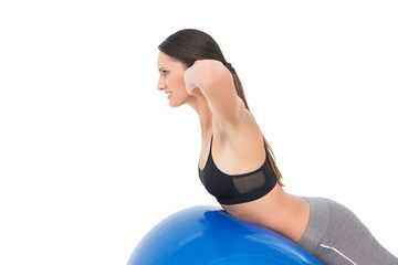 Fototapeta na wymiar Side view of a fit woman stretching on fitness ball