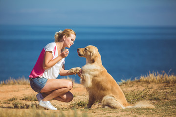 Beautiful woman with her dog playing on the sea shore. Outdoor p