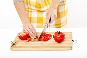 Woman cook's hands slicing the tomatoes on a wooden board