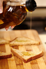 Cook's hand holding a bottle of olive oil and pouring it over sl