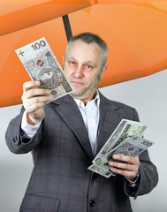 Businessman under umbrella with money in his hand