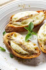 Crostini with fish, mozzarella and oregano