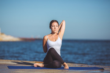 Fototapeta na wymiar Young beautiful woman on the beach making yoga