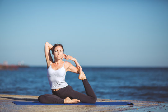 Young beautiful woman on the beach making yoga