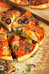 Homemade pizza with tomato, black olives and herbs