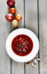 Top view on beetroot soup on old wooden table. Garlic and onions