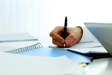 Closeup image of mans hand writing in notebook
