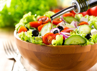 oil pouring into bowl of vegetable salad