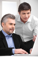 Young businessman showing his boss something on laptop.