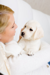 Close up of woman in white sweater embracing white puppy