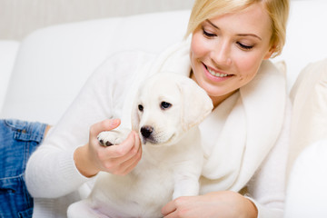 Woman is on the white leather sofa with white puppy