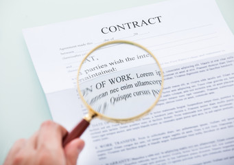 Hand Holding Magnifying Glass Over Contract