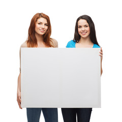 two smiling young girls with blank white board