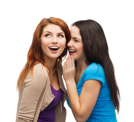 two smiling girls whispering gossip