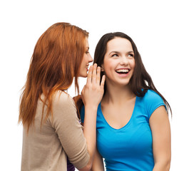 two smiling girls whispering gossip