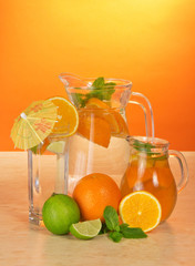 Jugs with drink, glass and a citrus