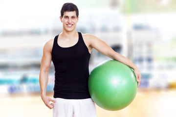 Young athletic man exercising workout fitness ball at the gym