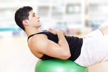Young athletic man exercising workout fitness ball at the gym